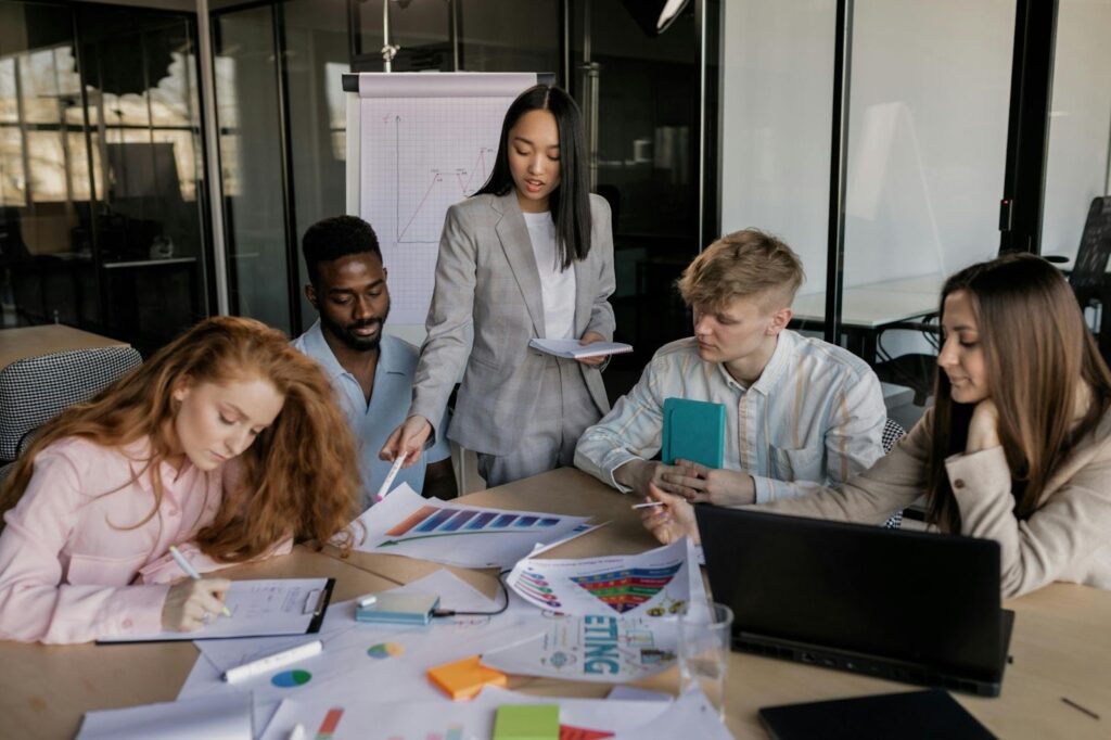 A marketing strategist presenting campaign data to a creative team in a modern office setting with charts and laptops.