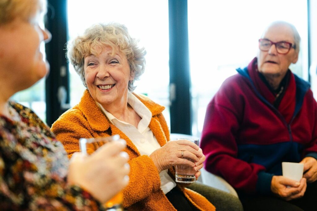 Seniors enjoying coffee together indoors, smiling and talking at a retirement residence.